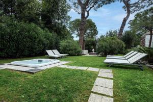 a garden with two benches and a tub in the grass at Catullo 18 Apartment, Garda Lake, Jacuzzi, Fitness, Ac in Desenzano del Garda