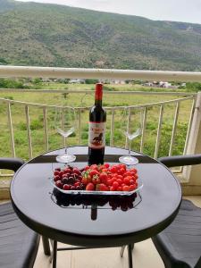 a table with a plate of tomatoes and a bottle of wine at Apartman Cherine in Mostar