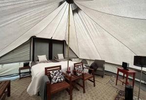 a bedroom with a tent with a bed and chairs at Godaland Glamping in Hvolsvöllur