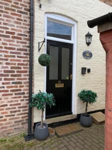 a black door with two potted plants in front of it at Hideaway Cottage Bewdley with parking near the River Severn in Bewdley