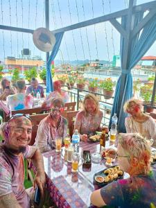 um grupo de pessoas sentadas à mesa com tinta em Yog Hostel em Catmandu