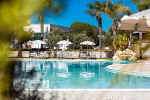 einen Pool in einem Resort mit Stühlen und Sonnenschirmen in der Unterkunft Borgo Mulino a Vento - Resort in Uggiano la Chiesa