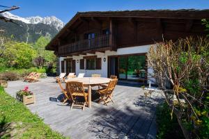 eine Terrasse mit einem Tisch und Stühlen sowie ein Haus in der Unterkunft Chalet 280m2 Sauna Cinema 12pax Heart of Les Praz in Chamonix-Mont-Blanc