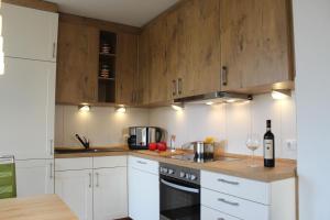 a kitchen with white cabinets and a bottle of wine at Haus Schwalbennest in Dassow +17 photos