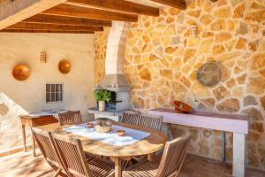 een eetkamer met een tafel en een stenen muur bij Marina Ses Covetes in Campos