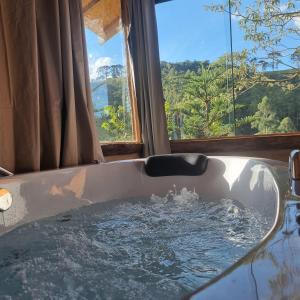 a bath tub with a view of a mountain at Chalés Fenix in Santo Antônio do Pinhal
