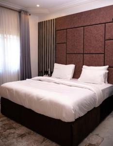 1 dormitorio con 1 cama grande con sábanas y almohadas blancas en Duplex16 en Enugu