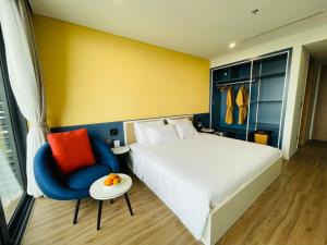 a hotel room with a bed and a blue chair at Flamingo Ibiza Hải Tiến in Thanh Hóa