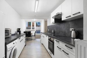 a kitchen with white cabinets and black counter tops at Ferienhaus Doris in Bad Urach