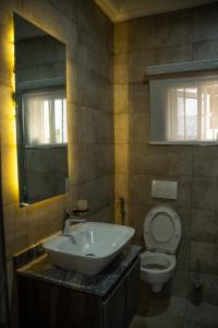 a bathroom with a sink and a toilet and a mirror at Duplex16 in Enugu