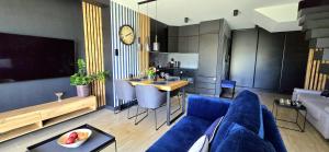 a living room with a blue couch and a kitchen at Apartament Bursztynowy Jantar by TriApart in Jantar