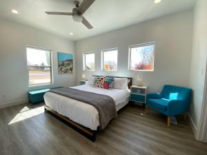 ein Schlafzimmer mit einem Bett und einem blauen Stuhl in der Unterkunft Timber & Tin E 2Bed 2Bath w Pool & Rooftop Deck in Kanab