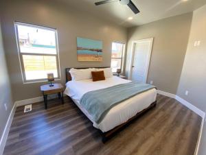 a bedroom with a large bed and two windows at Timber & Tin G 2Bed 2Bath w Pool & Rooftop Deck in Kanab