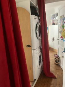 a laundry room with a washing machine and red curtains at Appartement chateau de Vincennes JEUX OLYMPIQUES in Vincennes