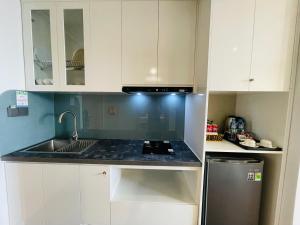 a kitchen with white cabinets and a sink at Flamingo Ibiza Hải Tiến in Thanh Hóa