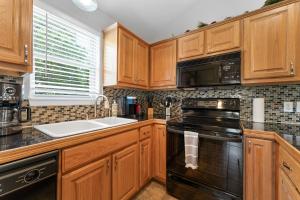 a kitchen with wooden cabinets and a black stove top oven at Heavenly Hideaway Condo in Branson West