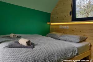 two beds in a bedroom with a green wall at Base Camp - Glamping resort Bovec in Bovec