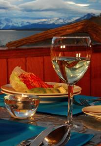 a table with a glass of wine and a plate of food at Weskar Lodge Hotel in Puerto Natales