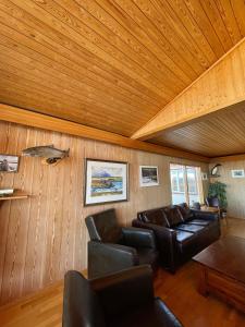 een woonkamer met lederen meubels en een houten plafond bij Vökuholt Lodge in Laxamýri