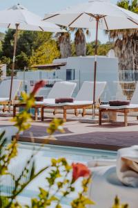 a group of chairs and umbrellas next to a pool at Nativo Hotel Ibiza in Santa Eularia des Riu