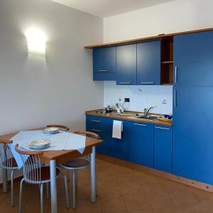 una cucina con armadi blu, tavolo e sedie di Jonio Vacanze Residence a Castellaneta Marina