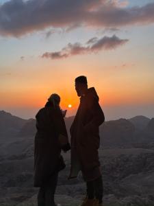 two people standing on top of a mountain at sunset at Petra Desert Dream Hotel in Wadi Musa