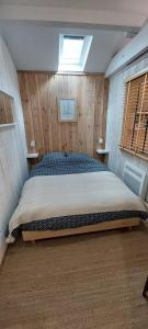 a bedroom with a bed in a room with wooden walls at La Cabane 14 in Lanton