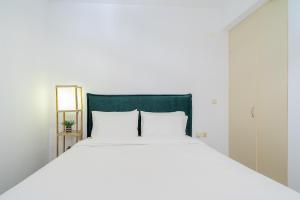ein weißes Bett mit einem grünen Kopfteil und weißen Kissen in der Unterkunft Sueño Seaside Residence in Agia Pelagia