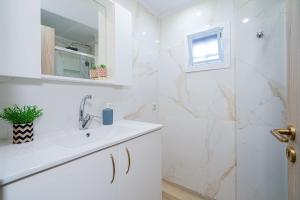 a white bathroom with a sink and a mirror at Sueño Seaside Residence in Agia Pelagia