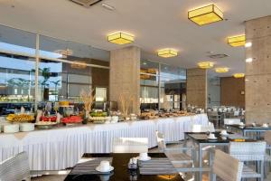 a restaurant with a buffet with tables and chairs at Apartamento Le Jardin in Caldas Novas