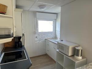 a small kitchen with a microwave and a window at Ferienbungalow Lais - Seite 1 in Loissin +10 photos