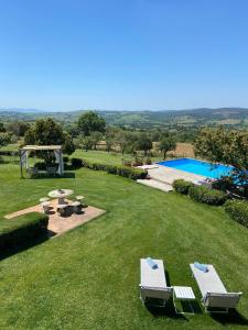 einen Garten mit zwei Gartenstühlen und einem Pool in der Unterkunft Tenuta Le Mandorlaie, Agriturismo in Scansano in Scansano
