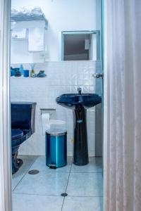 uma casa de banho com um lavatório azul e uma lata de lixo em Hostal Perlaschallay em Ayacucho