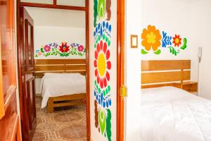 Habitación con cama y dormitorio con flores en la pared. en Hostal Perlaschallay, en Ayacucho