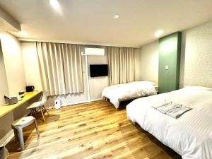 una camera d'albergo con 2 letti e una scrivania di Resort Stay Spa Tsurumi a Beppu
