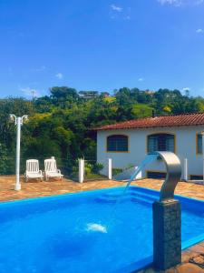 a swimming pool with a water fountain in front of a house at Pousada 3 Corações in Penedo