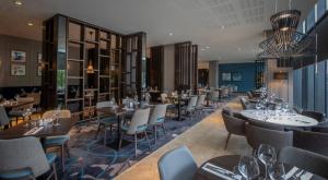 a restaurant with tables and chairs and a chandelier at Clayton Hotel Leopardstown in Leopardstown +19 photos