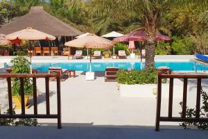 - une piscine avec des tables, des chaises et des parasols dans l'établissement Ocean Lodge Resort, à Cap Skirring