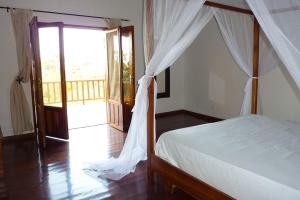 a bedroom with a canopy bed and a balcony at Ocean Lodge Resort in Cap Skirring