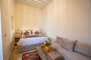 a bedroom with a bed and a couch and a table at Riad Babette in Essaouira