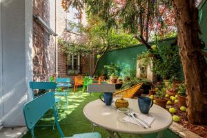 a patio with a table and chairs and a tree at Hotel Olympic Paris Boulogne by Patrick Hayat in Boulogne-Billancourt