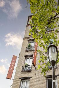 un edificio alto de ladrillo con ventanas y luz de la calle en Hotel Olympic Paris Boulogne by Patrick Hayat, en Boulogne-Billancourt