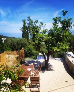 a patio with a table and chairs and a tree at Totolos home in Lazaratika Corfu in Áyios Pandeleḯmon