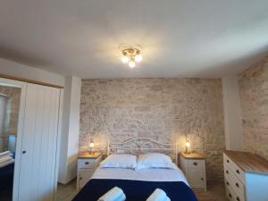 a bedroom with a bed and a stone wall at Bobelino in Povlja