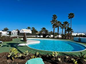 a large swimming pool with palm trees in the background at Villa Las Palmeras in Playa Blanca