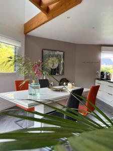 une salle à manger avec une table en verre et des chaises orange dans l'établissement CHAMBRE CHAMPÊTRE, à Angrie