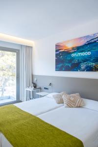 a bedroom with a white bed with a green blanket at Onmood Cala Ratjada - New Opening 2024 in Cala Ratjada