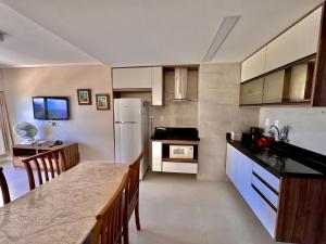 uma cozinha com uma mesa e um frigorífico branco em Ondina Apart Hotel Residences em Salvador