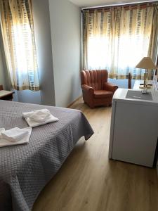 ブラガンサにあるSão Roque Hotel & Suitesのベッドルーム1室(ベッド1台、ソファ、椅子付)