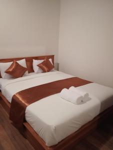 twee bedden met bruine en witte lakens en handdoeken erop bij Jepun Homestay Lemukih in Singaraja